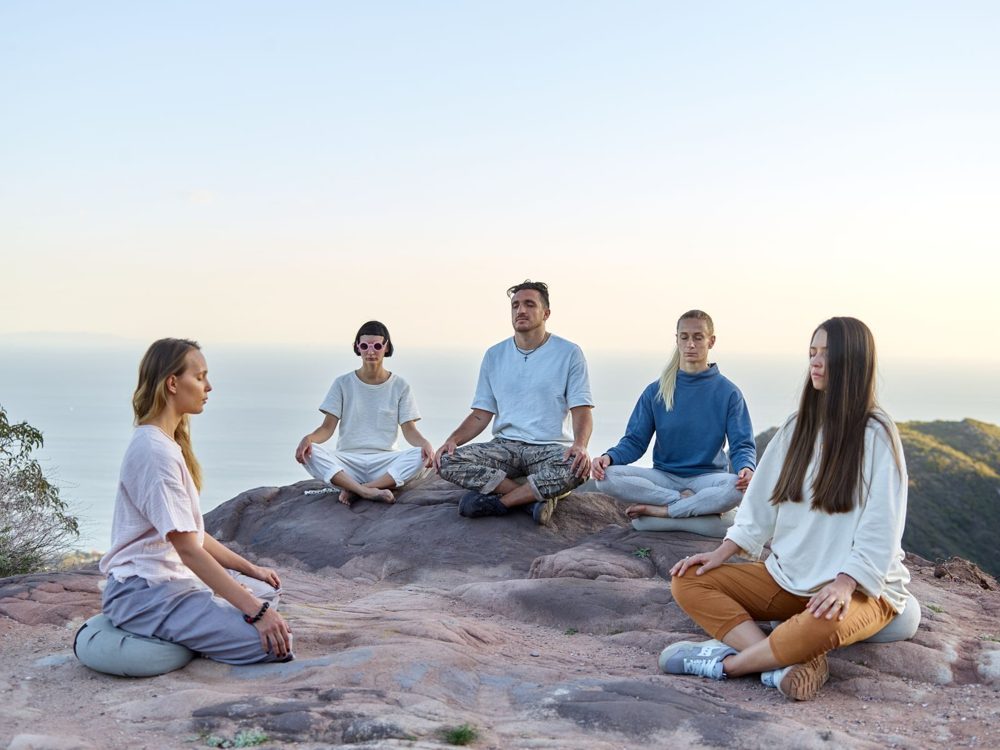A small group sitting in practice on a rock at dawn