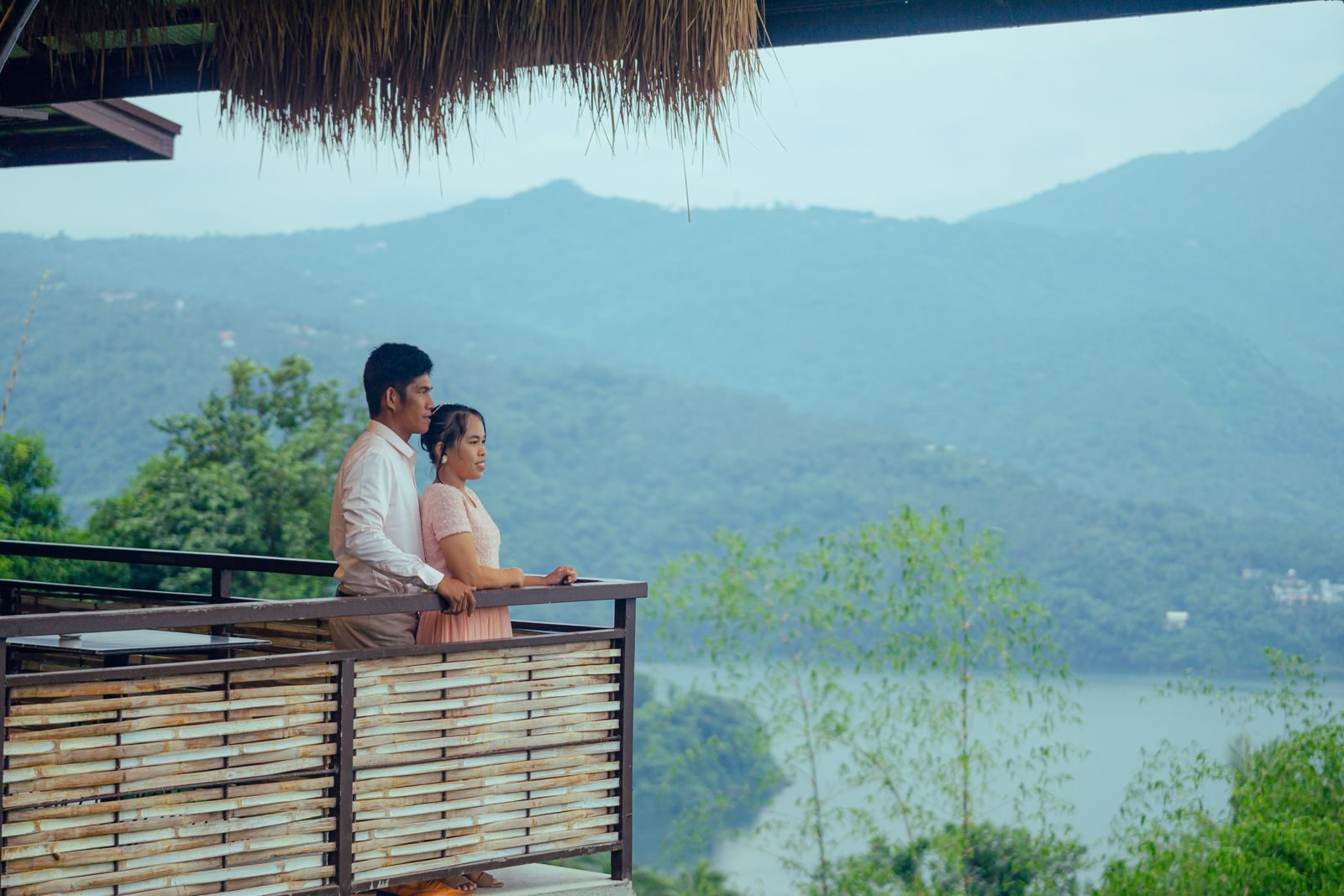A couple at a timber balcony above misty hills and water