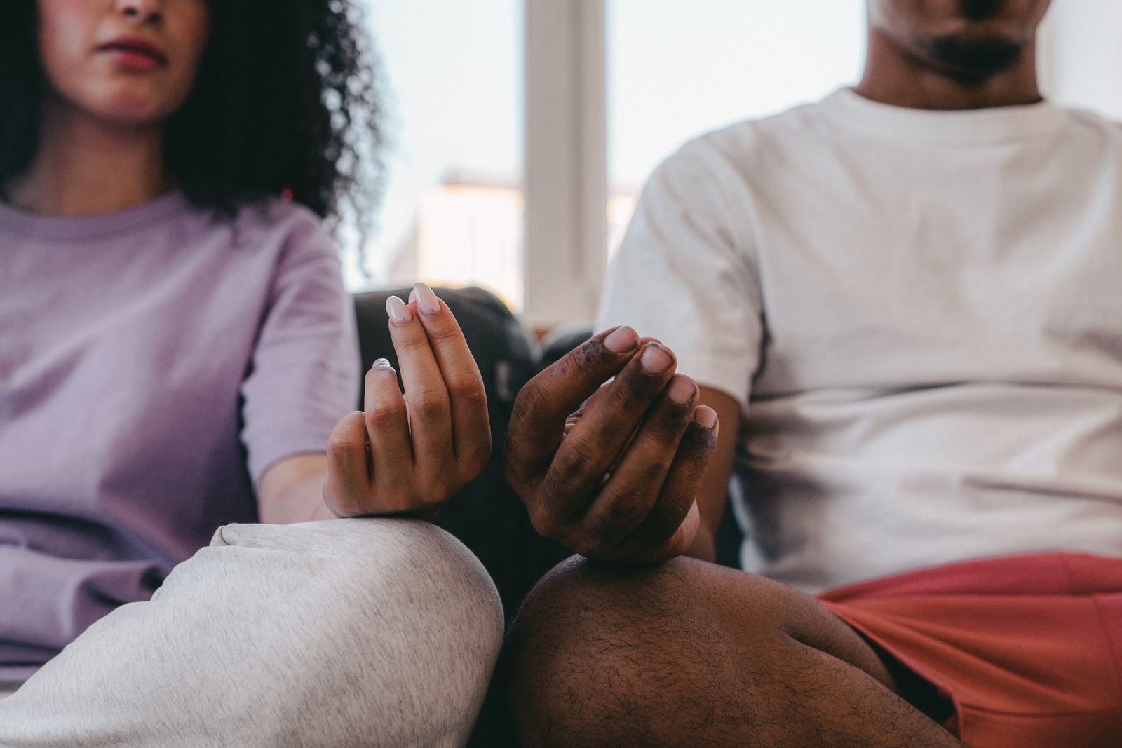 Two people side by side, hands in meditation