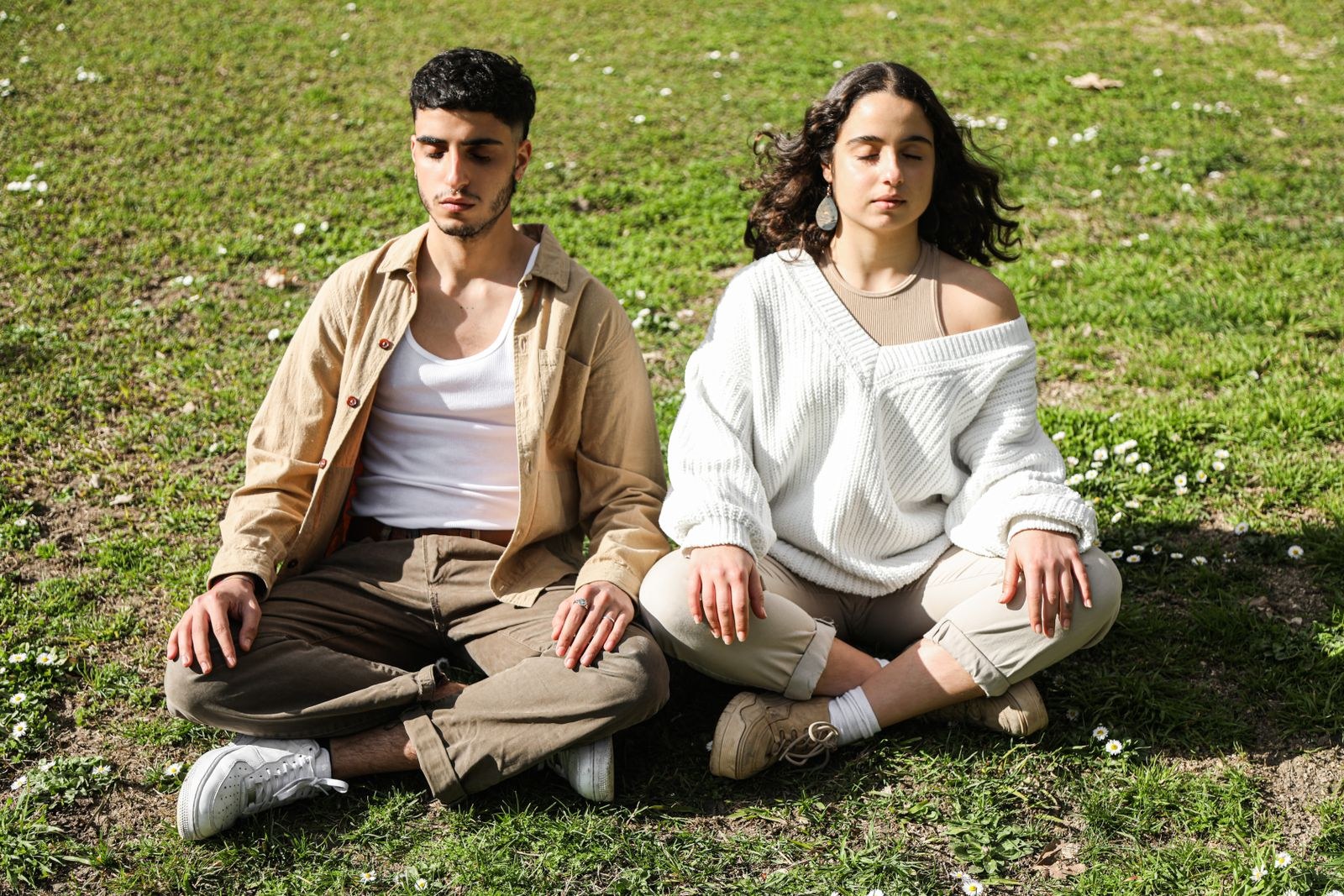 A couple sitting together on the grass, eyes closed