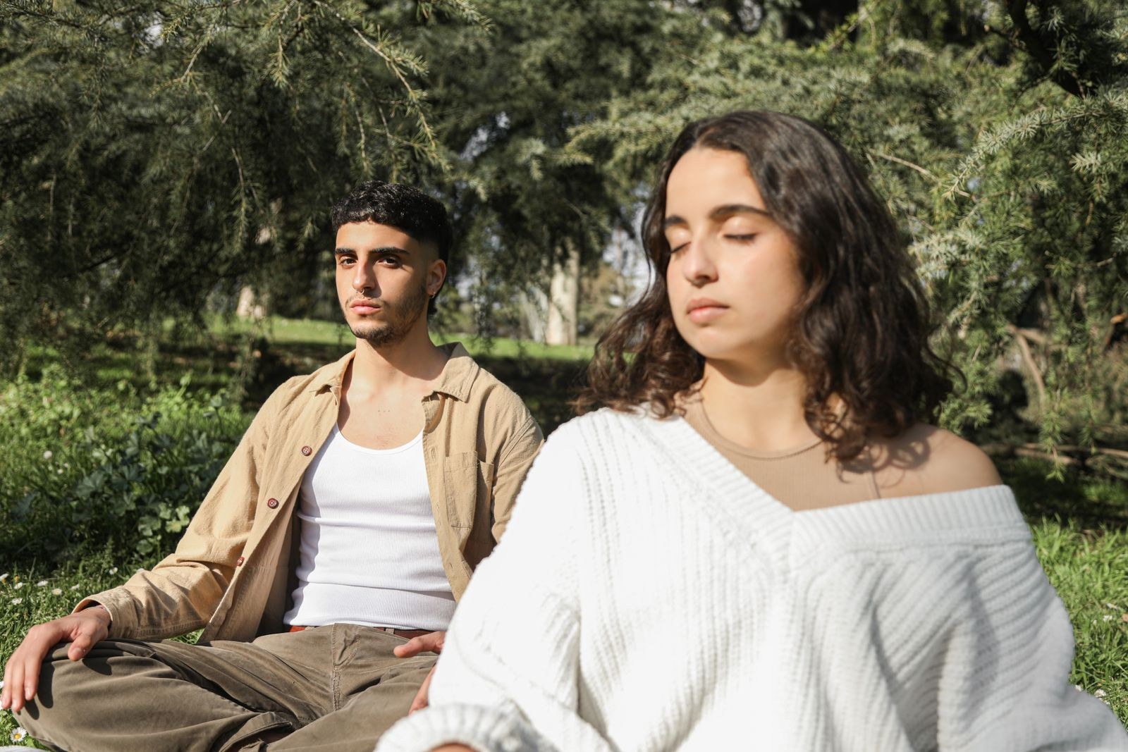 A couple sitting in meditation together under the trees