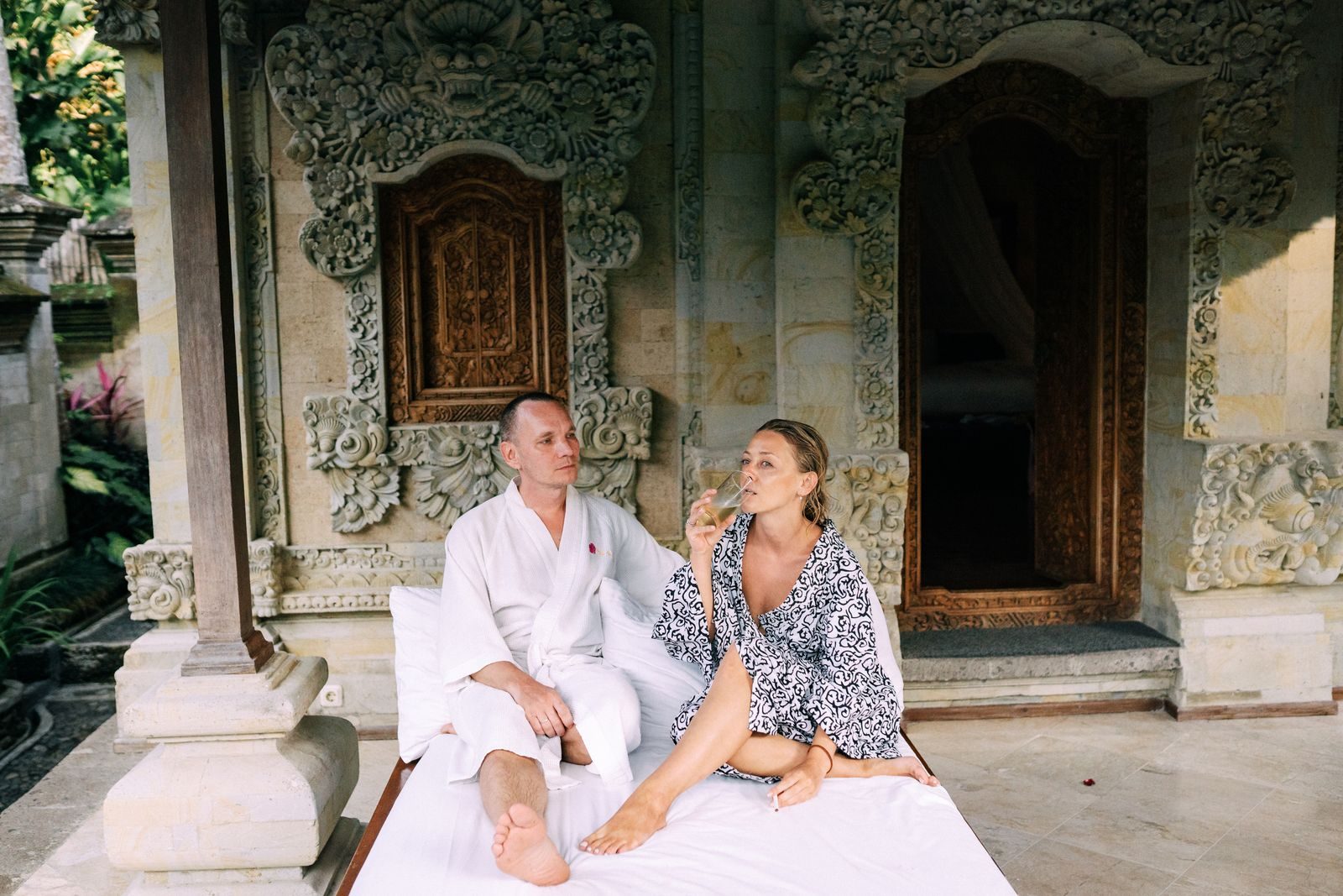 Two people in robes at the door of a tropical villa