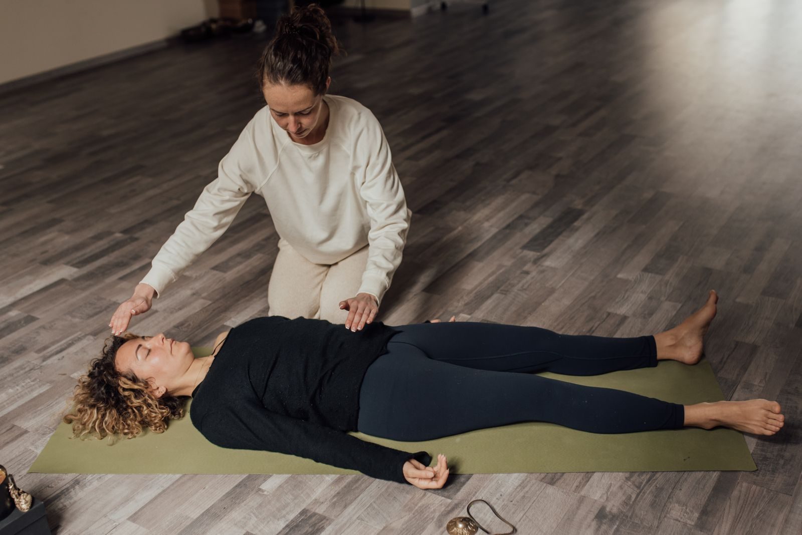 A practitioner with her hands on a woman lying on a mat