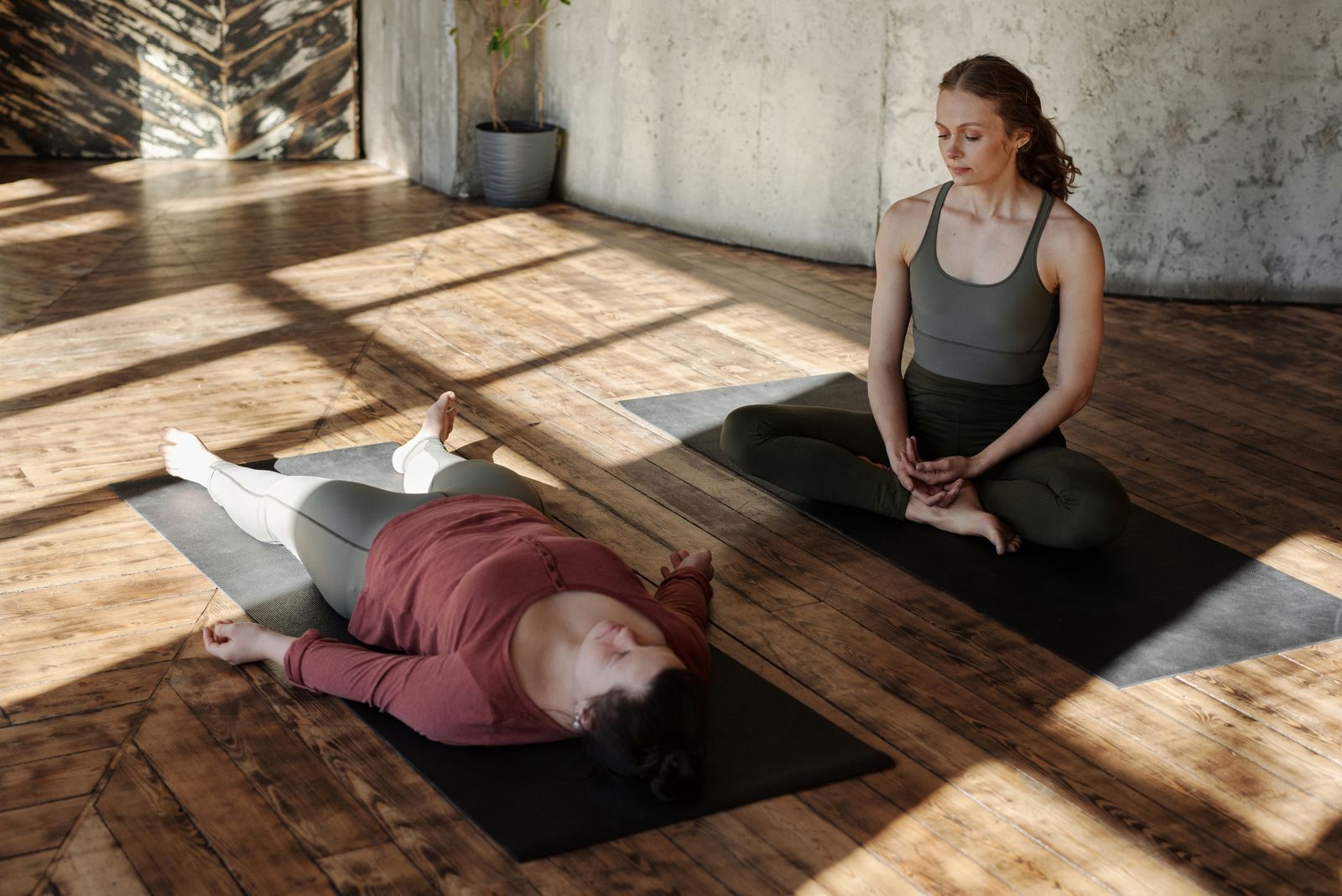 A sunlit studio, one person lying down, another sitting with her